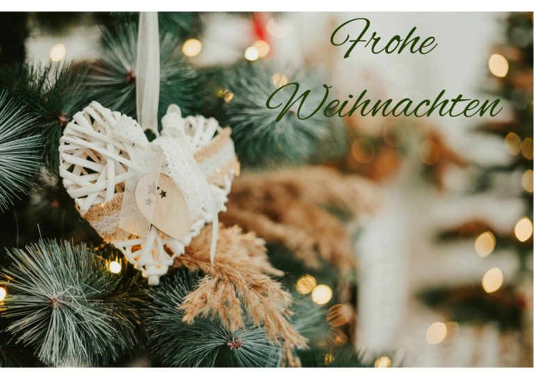 Teil eines Weihnachtsbaums mit Dekoration in Herzform, Lichtern und Schriftzug Frohe Weihnachten